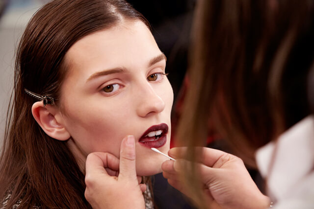 Maquilladora retocando labios con un palito de algodón